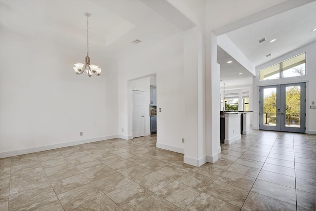 spare room featuring french doors, an inviting chandelier, a towering ceiling, and visible vents