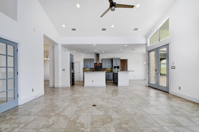 unfurnished living room featuring baseboards, visible vents, recessed lighting, ceiling fan, and a towering ceiling