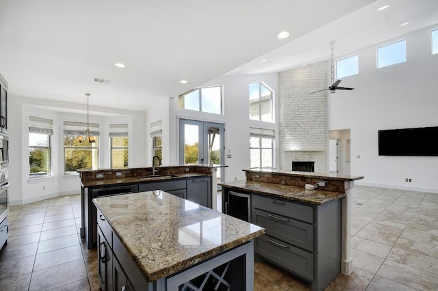 kitchen featuring a sink, visible vents, open floor plan, and a center island with sink