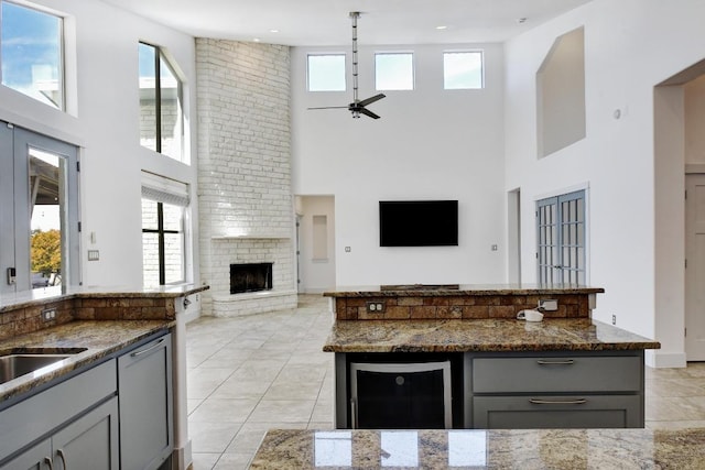 kitchen featuring dark stone countertops, a fireplace, open floor plan, and ceiling fan