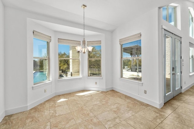 unfurnished dining area with light tile patterned floors, french doors, baseboards, and an inviting chandelier