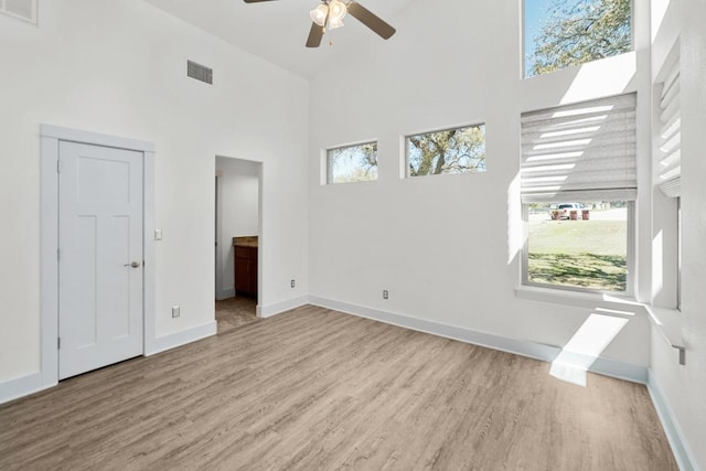 interior space featuring visible vents, a healthy amount of sunlight, a towering ceiling, and a ceiling fan