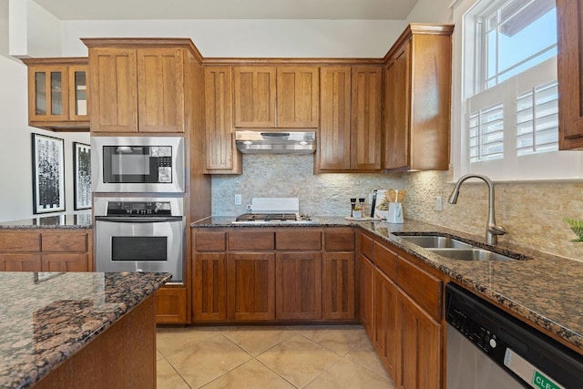 3129 Mill Stream Dr, Cedar Park, TX 78613 - kitchen with stainless steel appliances, under cabinet range hood, brown cabinetry, light tile patterned floors, and backsplash