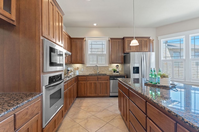 3129 Mill Stream Dr, Cedar Park, TX 78613 - kitchen with appliances with stainless steel finishes, brown cabinets, tasteful backsplash, dark stone counters, and recessed lighting