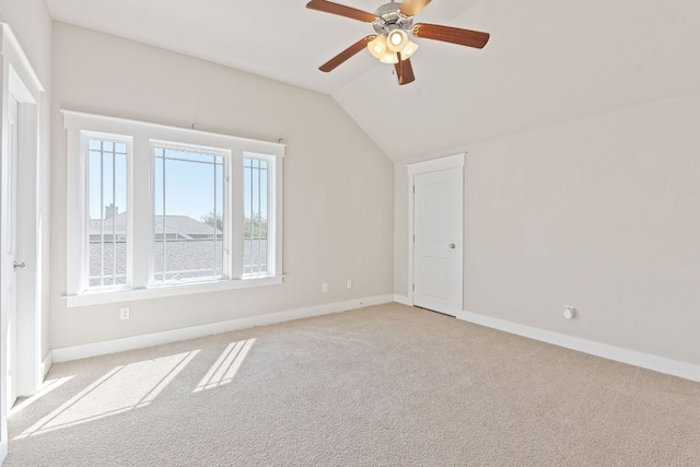 carpeted spare room featuring lofted ceiling, baseboards, and a ceiling fan