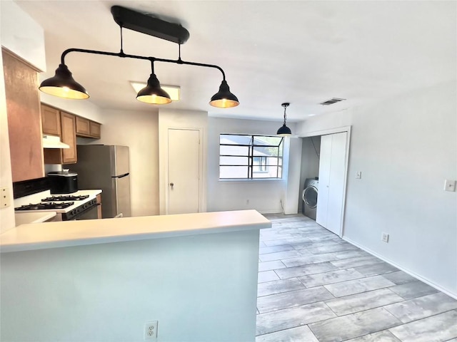 809 Bracewood Cir, San Marcos, TX 78666 - kitchen featuring visible vents, white range with gas cooktop, under cabinet range hood, freestanding refrigerator, and washer / dryer