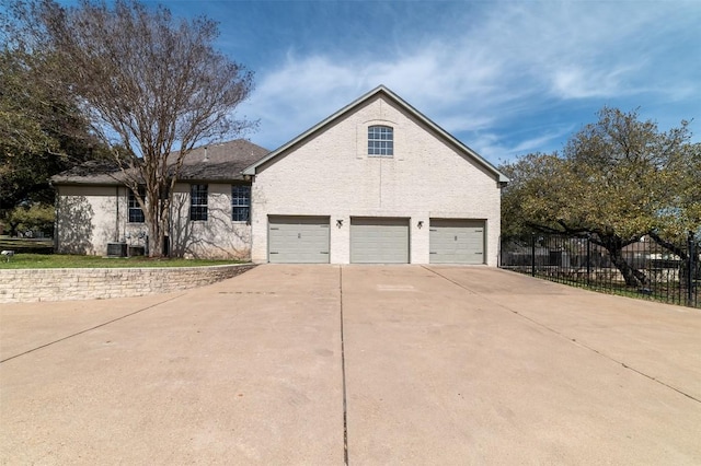 view of front facade featuring central AC, concrete driveway, a garage, and fence