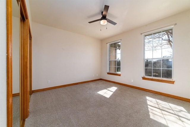 carpeted spare room with ceiling fan and baseboards