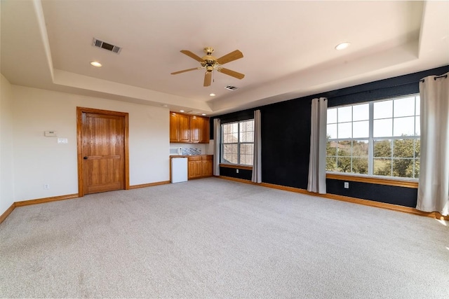 unfurnished living room featuring a raised ceiling, baseboards, and ceiling fan