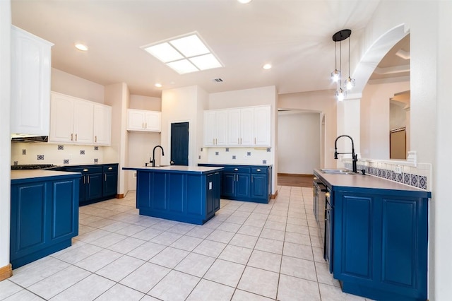 kitchen with blue cabinetry, a center island with sink, white cabinets, and a sink