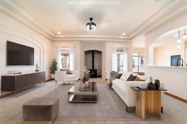 living area featuring a raised ceiling, a wood stove, and carpet