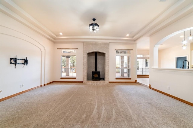 unfurnished living room with a tray ceiling, baseboards, and carpet