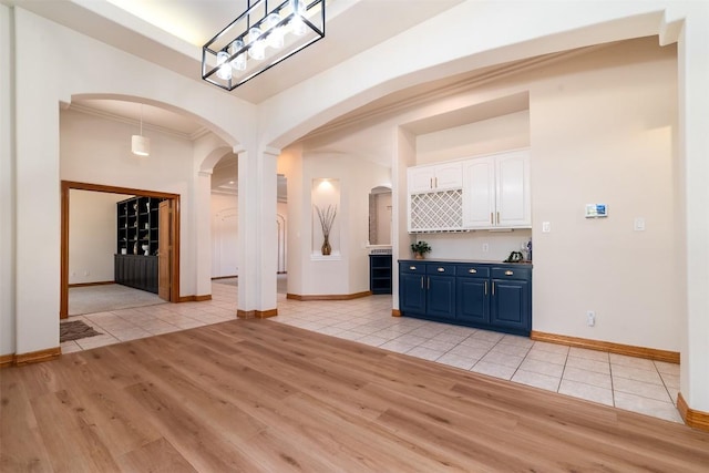 212 Cassidy Dr S, Georgetown, TX 78628 - unfurnished living room featuring arched walkways, light tile patterned floors, crown molding, and baseboards