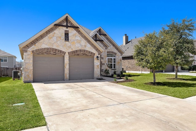 french country home with stone siding, a front yard, an attached garage, and driveway