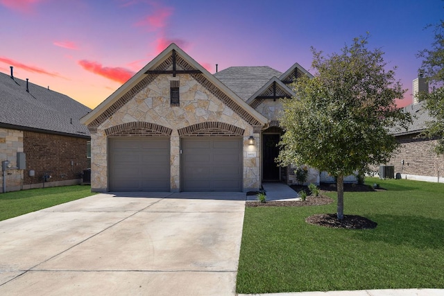 french country inspired facade featuring central air condition unit, a front lawn, stone siding, concrete driveway, and an attached garage