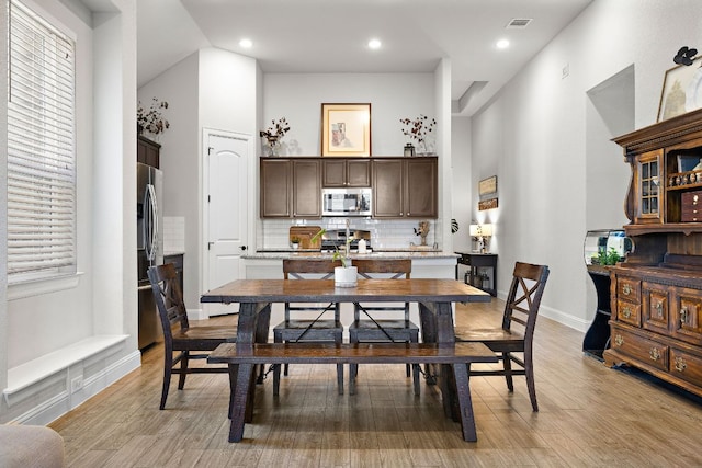 dining space with visible vents, high vaulted ceiling, light wood-style flooring, recessed lighting, and baseboards