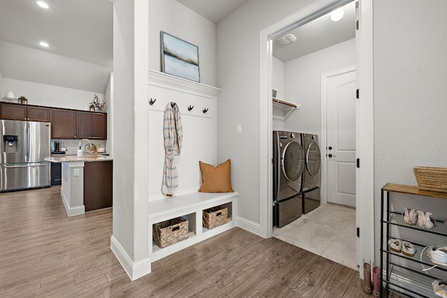 mudroom featuring light wood finished floors, independent washer and dryer, baseboards, and a sink