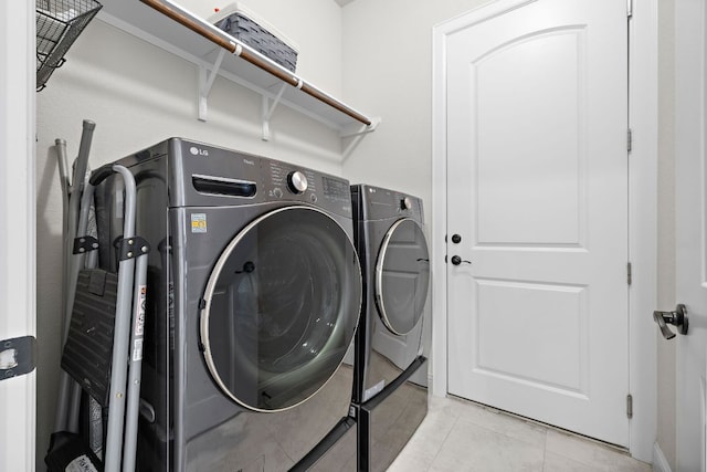 clothes washing area featuring washer and clothes dryer, laundry area, and light tile patterned flooring