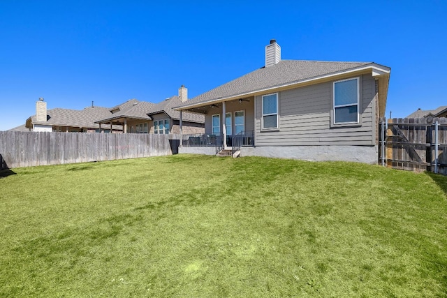 back of property featuring a lawn, a chimney, and fence