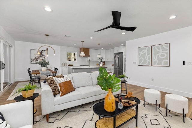 living area with recessed lighting, visible vents, and light wood-style floors