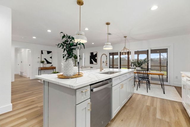 kitchen with light wood-type flooring, a center island with sink, a sink, stainless steel dishwasher, and recessed lighting