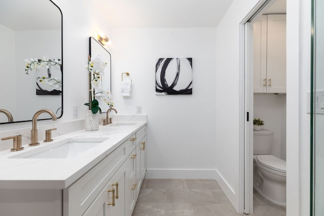 full bath featuring a sink, baseboards, toilet, and double vanity