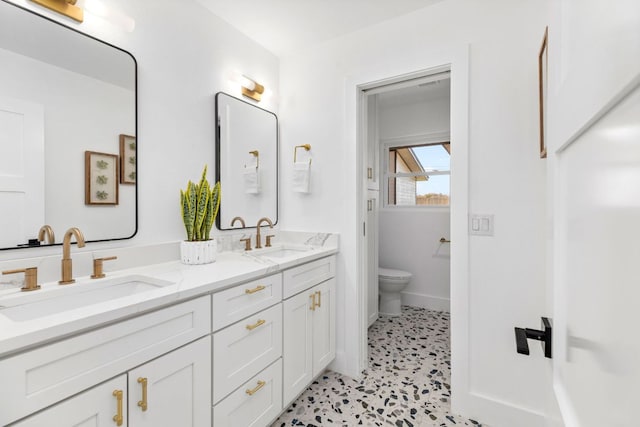 bathroom with a sink, toilet, and double vanity