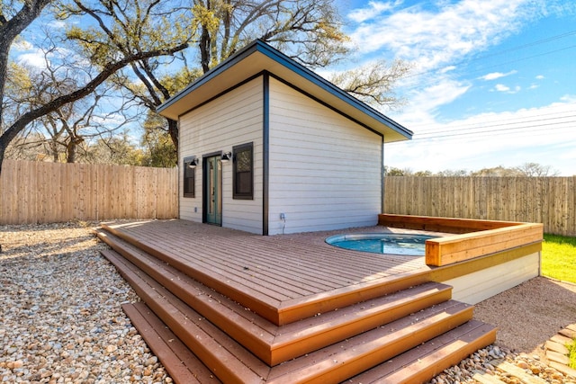 deck featuring an outbuilding, a hot tub, and a fenced backyard