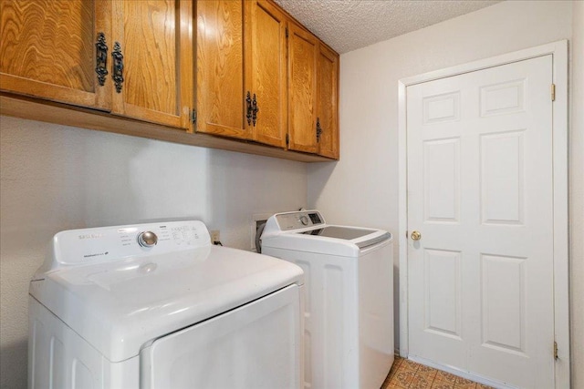 washroom featuring cabinet space, independent washer and dryer, and a textured ceiling