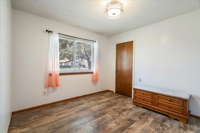 empty room featuring baseboards, dark wood-style flooring, and a textured ceiling