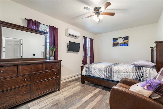 bedroom featuring baseboards, multiple windows, light wood-style floors, and an AC wall unit