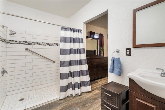 bathroom with vanity, wood finished floors, and tiled shower