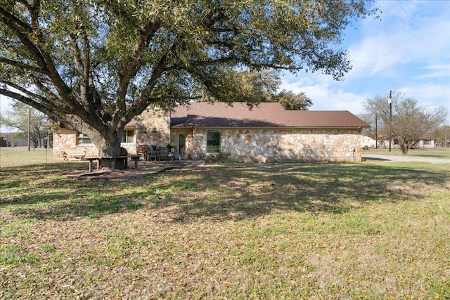 rear view of property with a patio area, stone siding, and a yard