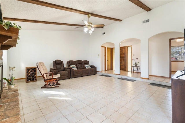 living room featuring a ceiling fan, visible vents, light tile patterned flooring, arched walkways, and a textured ceiling