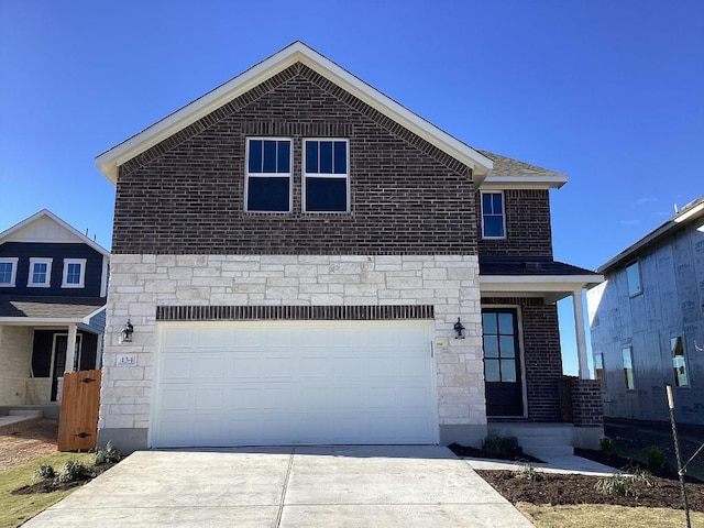 traditional-style home featuring brick siding, stone siding, an attached garage, and concrete driveway