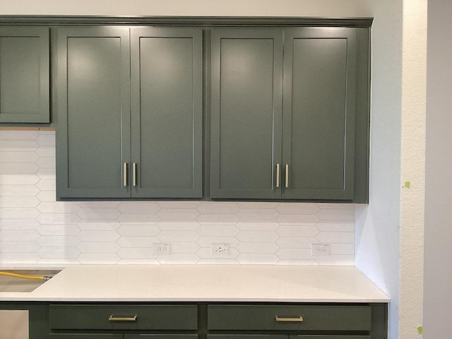 room details featuring backsplash, green cabinets, and light countertops