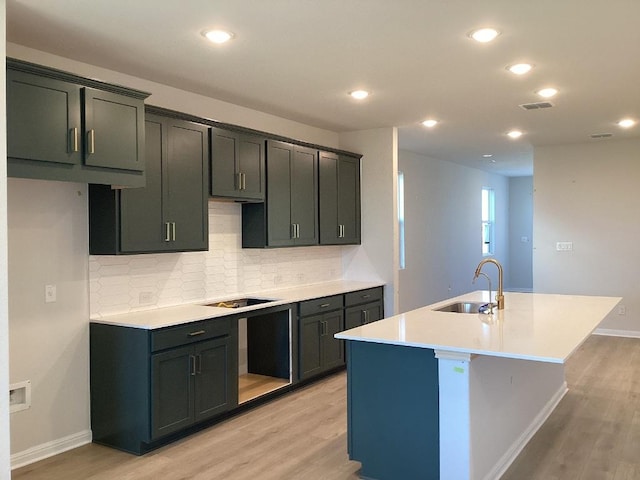 kitchen featuring a sink, visible vents, light wood-type flooring, and a kitchen island with sink