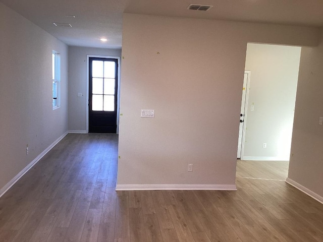 empty room with visible vents, baseboards, and wood finished floors