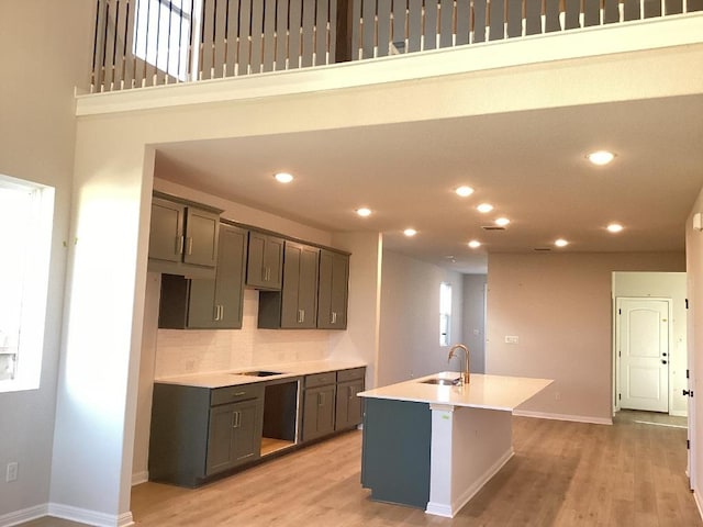 kitchen with a sink, light wood-type flooring, a kitchen island with sink, and recessed lighting