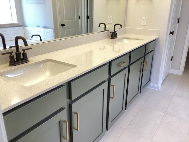 full bath featuring tile patterned flooring, double vanity, baseboards, and a sink