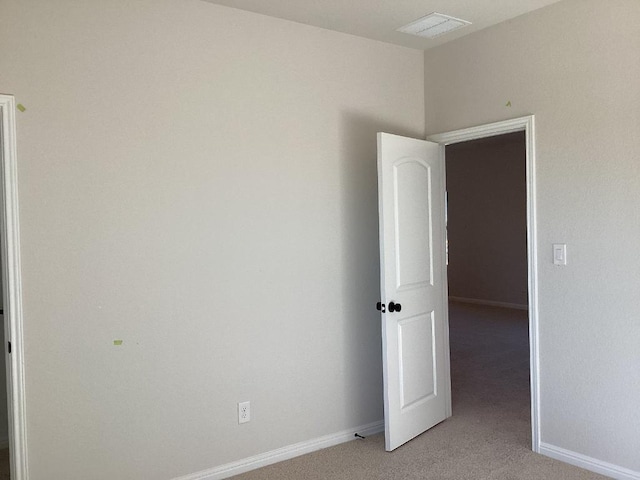 spare room featuring light carpet, visible vents, and baseboards