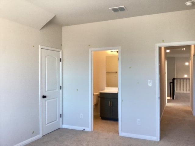 unfurnished bedroom with visible vents, light carpet, baseboards, and connected bathroom