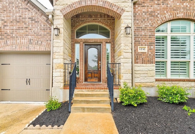 doorway to property with stone siding, a garage, brick siding, and driveway