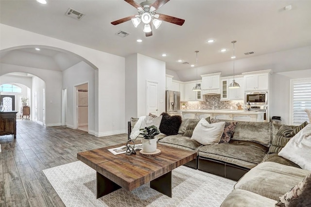 living room featuring arched walkways, visible vents, plenty of natural light, and ceiling fan