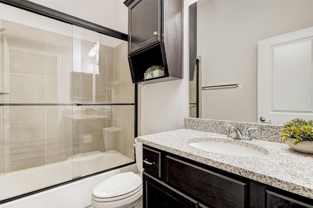 bathroom featuring combined bath / shower with glass door, toilet, and vanity