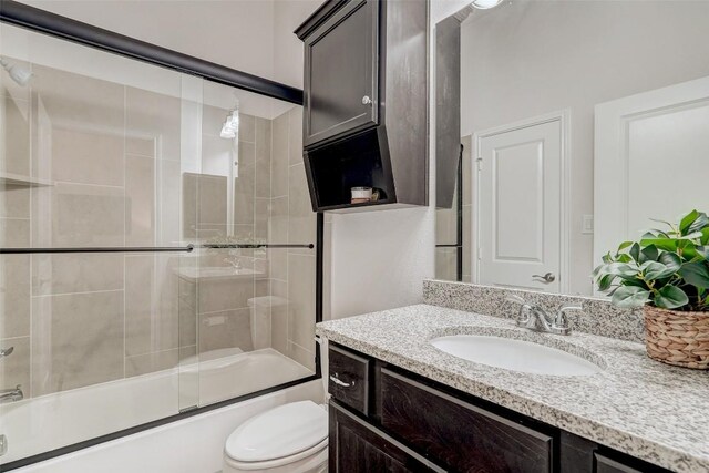 bathroom with toilet, vanity, and shower / bath combination with glass door