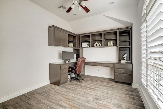 office space featuring baseboards, visible vents, light wood finished floors, ceiling fan, and vaulted ceiling