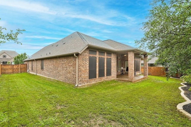 back of property with brick siding, a fenced backyard, a lawn, and a patio area