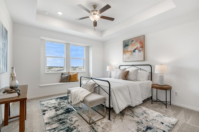 carpeted bedroom with baseboards, a raised ceiling, and ceiling fan