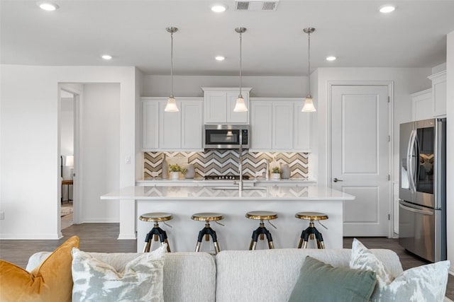 kitchen featuring visible vents, a kitchen island with sink, stainless steel appliances, white cabinets, and light countertops